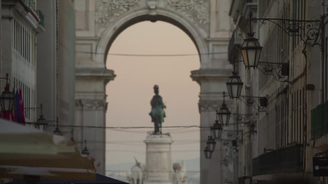 Slow motion tilt up from crowd to rack focus of statue under arch / Lisbon, Lisboa, Portugal