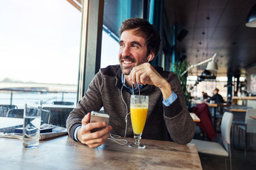 Positive and attractive middle aged businessman sitting in cafe bar and talking on the phone