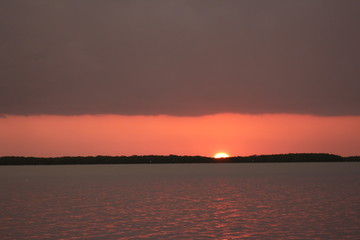 Sunset below dark gray storm clouds over rippling water