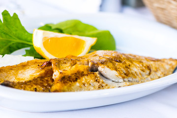 The trout fish served on the plate together with salat
