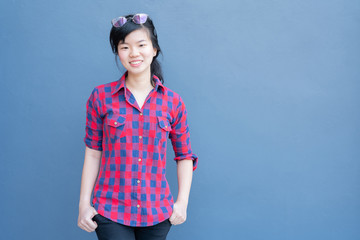 Obraz premium Attractive young asian woman wearing fashionable clothes and Sunglasses on hair posing on blue navy wall background with copy space text. A portrait of a beautiful asian woman smiling at camera.