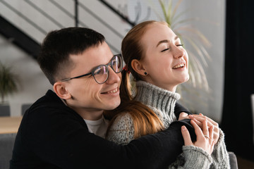 Close up head shot portrait of smiling happy young man and woman hugging and looking away. Attractive affectionate couple in love, romantic relationship and just married concept