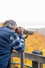 Fototapeta na wymiar Man looking through binoculars at scenic overlook (vertical)
