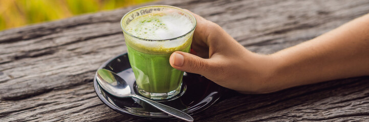 Women's Hand holding cup of matcha Latte, Green Tea, on old Wooden Background table BANNER, LONG...