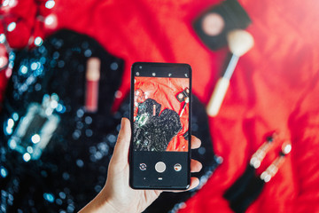 Close up of hand holding mobile phone making photos of cocktail dress.