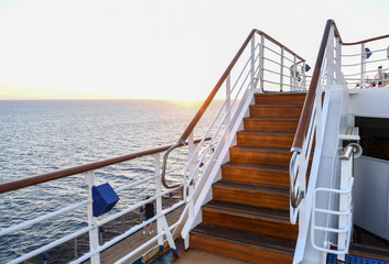 Railing and stairs of a cruise ship at sunset.