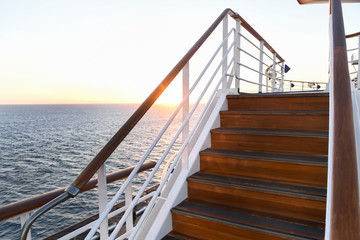 Railing and stairs of a cruise ship at sunset.