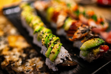 Sushi Rolls at restaurant. Luxury sushis with avocado and eel topping, rainbow maki, tuna, tobiko,...