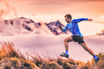 Sport runner trail running man in mountains cold clouds and hills. Male athlete training cardio jumping against altitude sky background. © Maridav