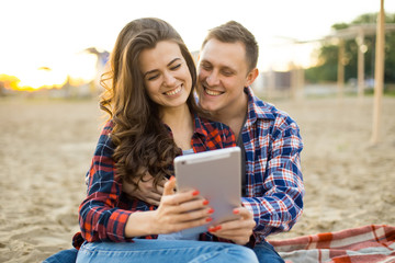 Loving couple using a tablet on the beach