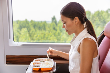 Train commute bus travel Asian business woman eating asian food meal with chopsticks....