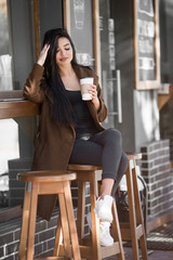 Naklejka na ściany i meble Beautiful girl drinks coffee, sitting in a cozy cafe.