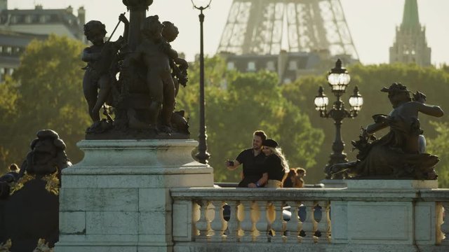 Happy couple posing for cell phone selfie near statues on Pont Alexandre / Paris, Ile de France, France