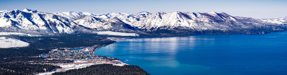 Aerial view of Lake Tahoe on a sunny winter day, Sierra mountains covered in snow visible in the...