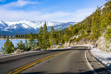 Travelling on the shoreline of Lake Tahoe on a winter day; Sierra mountains covered with snow...
