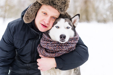 Caucasian man hugging gorgeous husky dog in winter day.