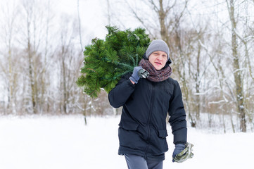 Fototapeta na wymiar Man in the hands of carries Christmas tree in the winter forest.