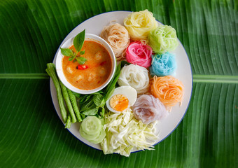 thai rice noodle colorful or rice vermicelli noodle and fish curry soup sauce with vegetable on plate