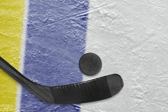 Hockey stick, puck and fragment of the ice arena with yellow and blue lines