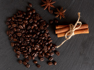 Top view of roasted coffee beans, anise and cinnamon sticks on stone surface