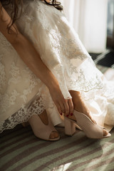 bride puts on her beige wedding shoes