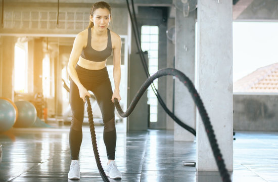 Strong and slim woman using battle rope at gym,Female doing exercise in functional training