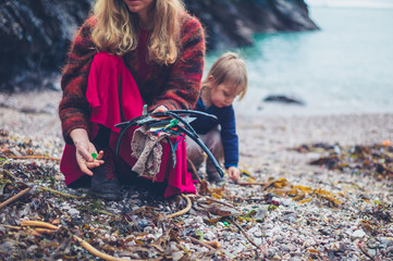 Young mother and toddler cleaning up rubbish on beach