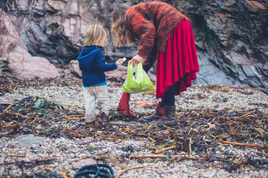 Young mother and toddler cleaning up rubbish on beach