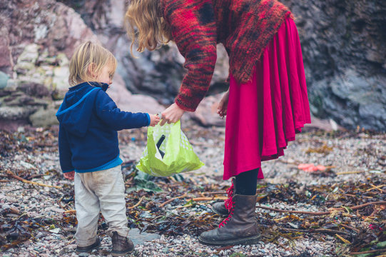 Young mother and toddler cleaning up rubbish on beach