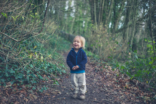 Little toddler standing on path in the woods