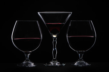 Silhouette of  three drinking glass and red wine on black background 