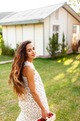 Beautiful girl with long hair enjoying summer day in a country house and eats strawberries. unity with nature. The woman inhales fresh air. The woman enjoys living.