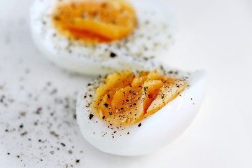 Hard boiled eggs springkled with black pepper on a white background, close up - Powered by Adobe