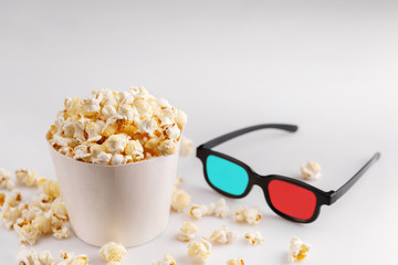 Snack to watch movies. Popcorn in a white bucket and glasses on a white background.