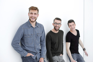 three people leaning against the wall, smiling
