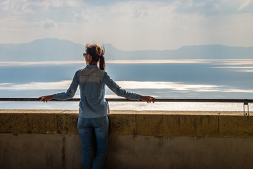 Young woman relaxing on balcony of castle on mediterranean sea.