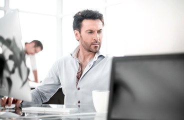 business man talking to a colleague sitting at his Desk