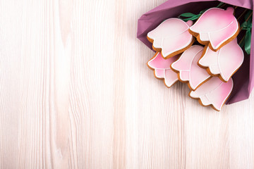 Bouquet from pink gingerbread cookies in the shape tulips on wooden table with copy space. Top view