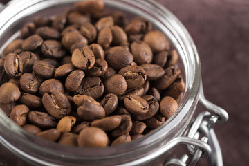 Glass jar with roasted coffee beans.