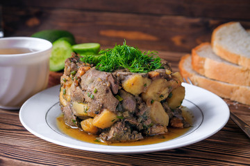 Fried chicken liver and onions with potatoes as close-up in a plate on wooden table