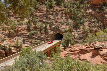 red car on the bridge over Pine Creek Gorge at the entrance of the Zion - Mount Carmel Tunnel in...