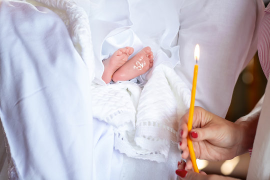 A fragment of a photograph of a little girl preparing for a baptismal ceremony, her legs on a white dress, baptism