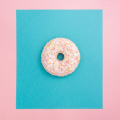 Delicious donut with icing and candy on a pink and blue background. Square lighting background.