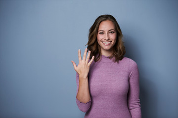 Beautiful woman using fingers to show five, studio