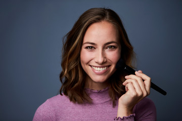 Obraz premium Stunning smiling brunette applying make up, portrait