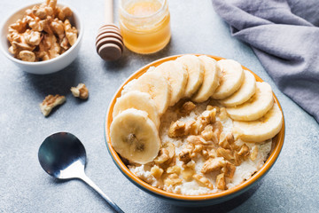 Healthy breakfast. Cottage cheese with banana and walnuts on grey background.