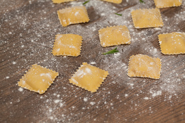 Tasty raw ravioli with flour on wooden background. Process of making italian ravioli. Selective focus