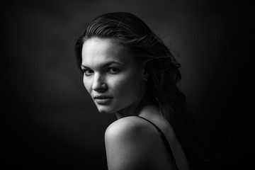 Dramatic black and white portrait of a beautiful girl on a dark background