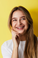 Laughing young lady against yellow background