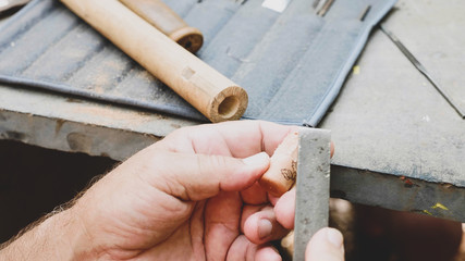 Male hands is grinds the cork by file to make a handiwork flute, close-up